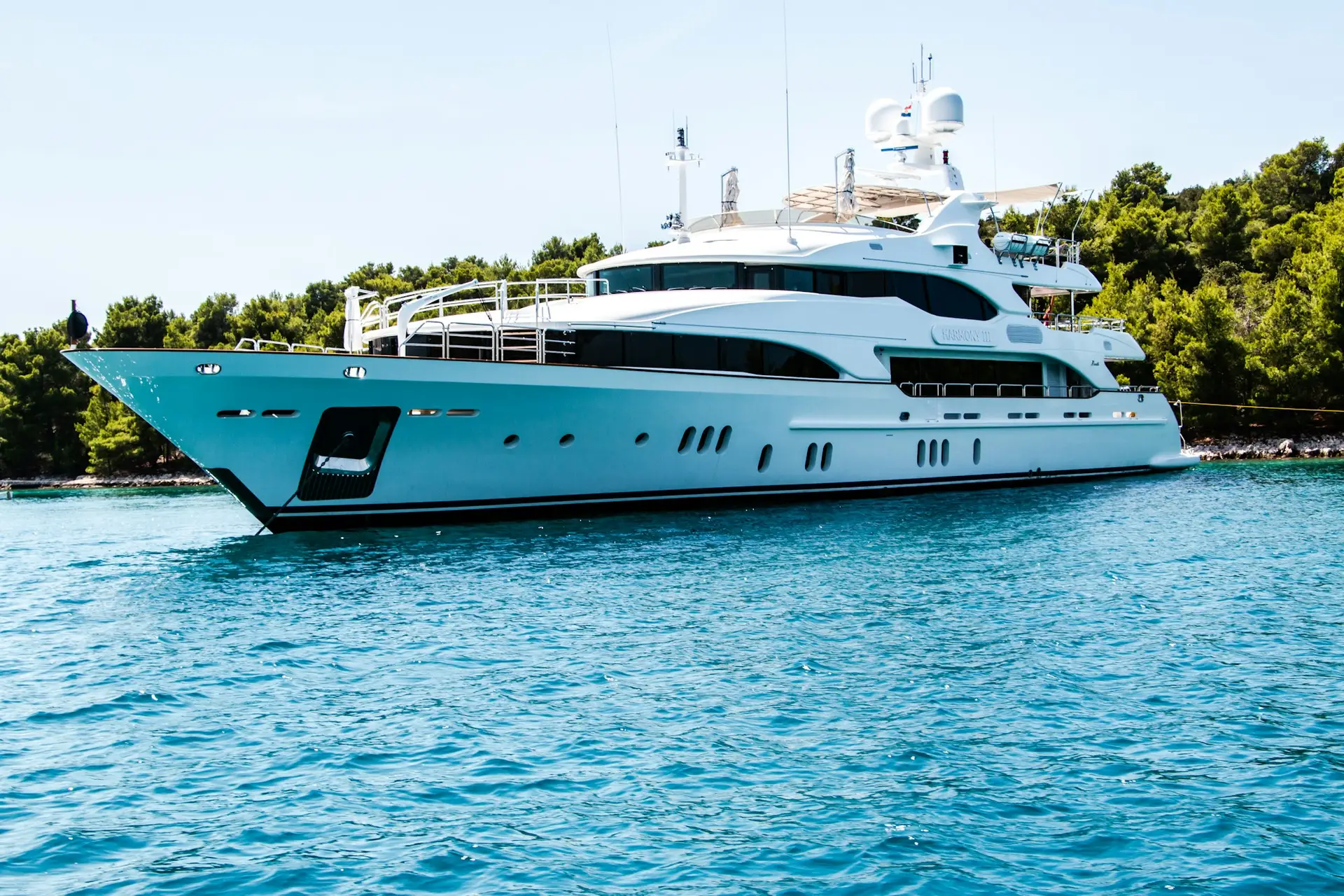 White motor yacht by the green Adriatic shore